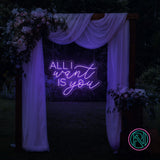 LED-neonskilt med tekst “ALL I want IS you” i fiolblått lys.