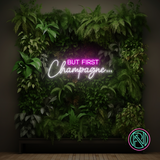 LED-neonskilt med teksten «BUT FIRST Champagne…» i hvitt og rosa lys