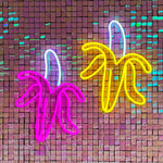 LED-neonskilt i bananform med gult, rosa og blått lys.
