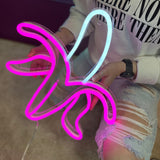 LED-neonskilt 'Banan' i hot pink og blå lys, med strømledning