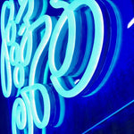 Nærbilde av LED-neonskrift «Good Vibes Only» i lyseblått lys.