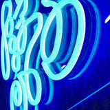 Nærbilde av LED-neonskrift «Good Vibes Only» i lyseblått lys.