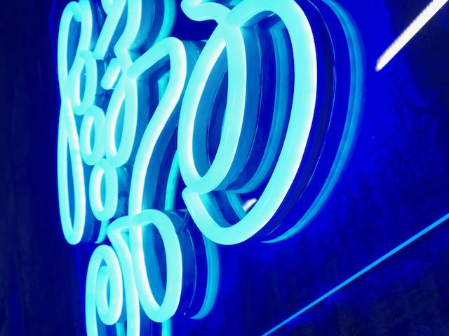 Nærbilde av LED-neonskrift «Good Vibes Only» i lyseblått lys.
