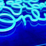 Nærbilde av LED-neonskrift i blått lys på neonskilt.