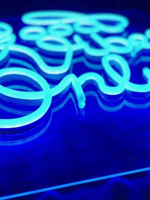 Nærbilde av LED-neonskrift i blått lys på neonskilt.
