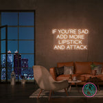 Neonskilt med «IF YOU’RE SAD» og «ADD MORE LIPSTICK AND ATTACK» i kjølig hvitt