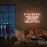 Neonskilt med «IF YOU’RE SAD» og «ADD MORE LIPSTICK AND ATTACK» i kjølig hvitt