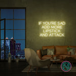 Neonskilt med «IF YOU’RE SAD» og «ADD MORE LIPSTICK AND ATTACK» i isblå