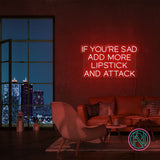Neonskilt med «IF YOU’RE SAD» og «ADD MORE LIPSTICK AND ATTACK» i rødt