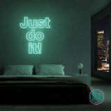 LED-neonskilt med teksten “Just do it!” i lys turkisgrønt lys.