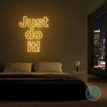 LED-neonskilt med teksten “Just do it!” i varm gul belysning.