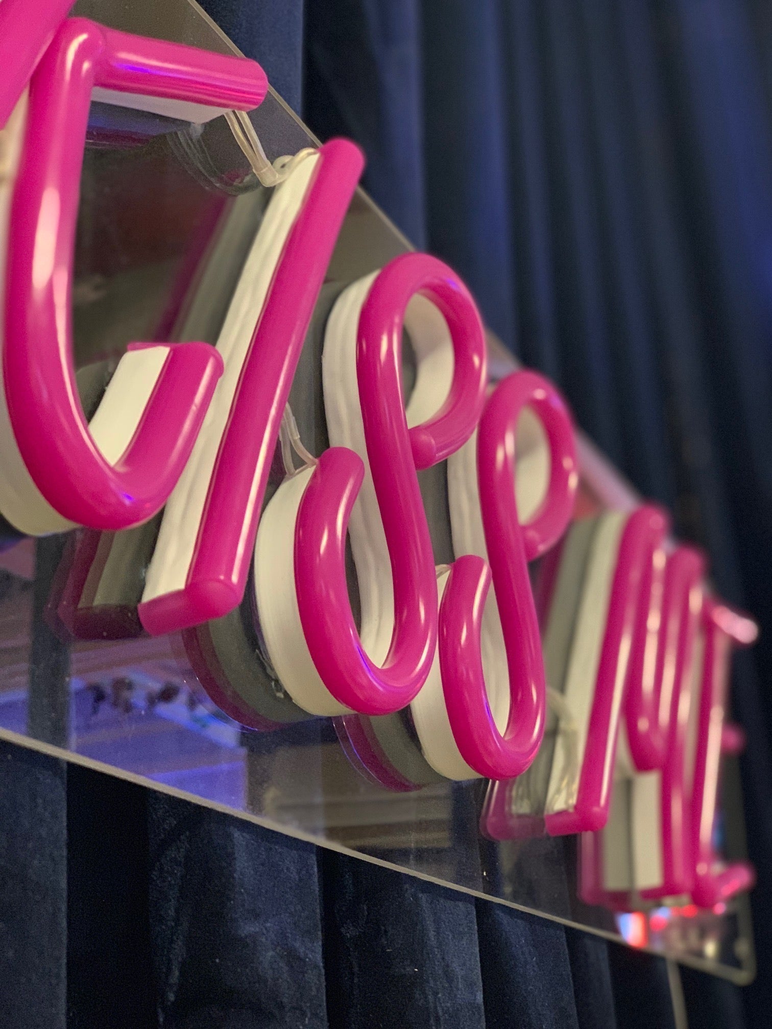 LED neonskilt i rosa, nærbilde av «Kiss ME»-bokstaver på klar plate