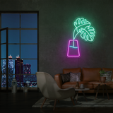 LED-neonskilt med vase og monstera-blader i grønt og rosa, opplyst kontur