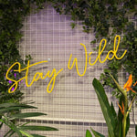LED neonskilt med «Stay Wild» i gult lys