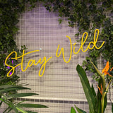 LED neonskilt med «Stay Wild» i gult lys