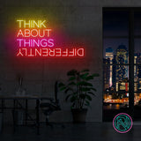 LED neonskilt med fargerik tekst «THINK ABOUT THINGS», oppslått på vegg.