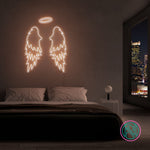 LED neonskilt med vingemotiv i hvitt lys.