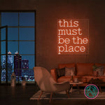 LED-neonskilt med teksten "this must be the place" i rød/oransje glød.