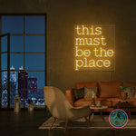 LED-neonskilt med teksten "this must be the place" i gulaktig glød.